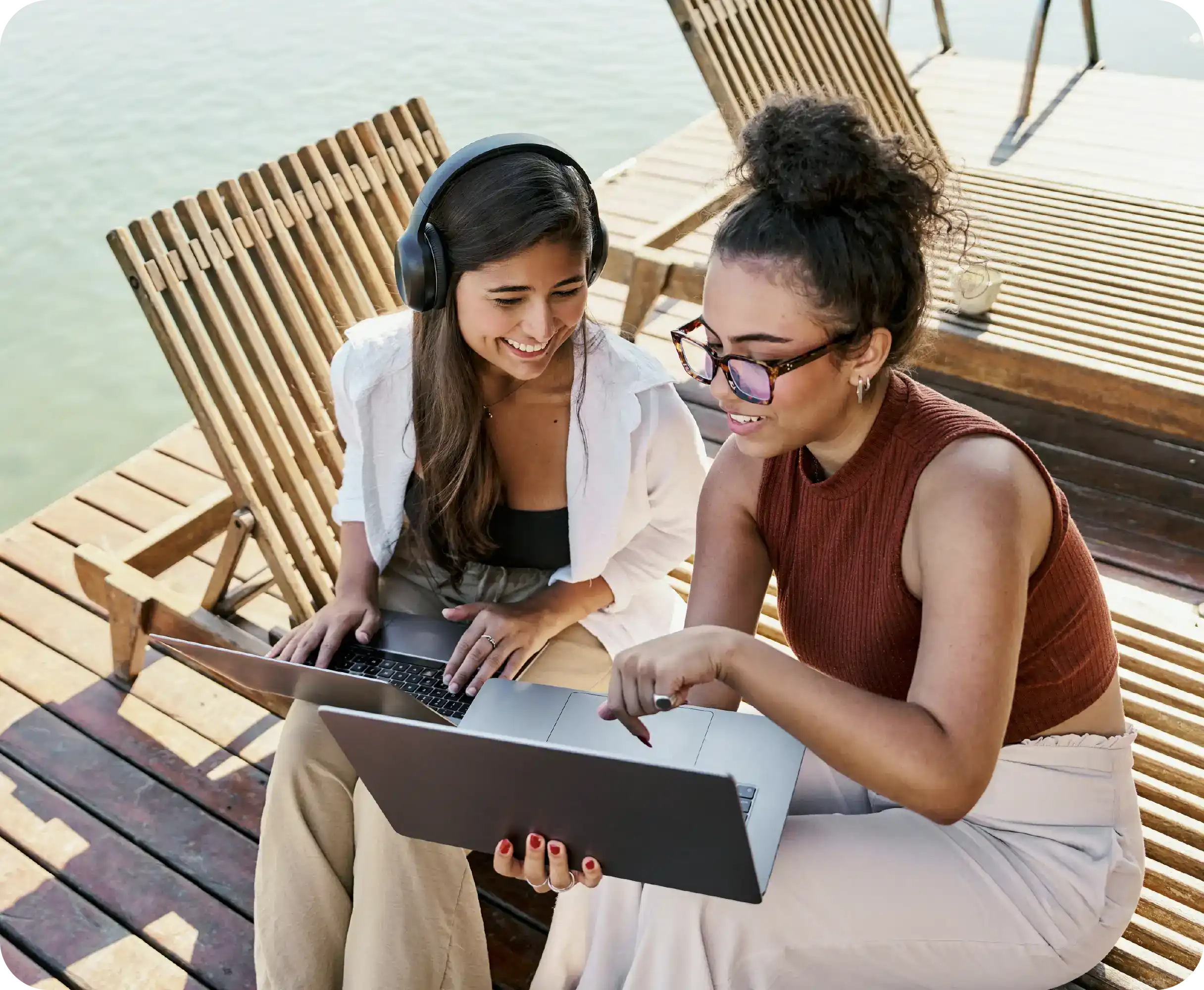 Two people working remotely laughing together in beach chairs