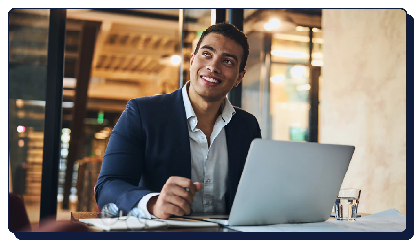 Smiling man works on computer and speaks on phone for his fully remote job